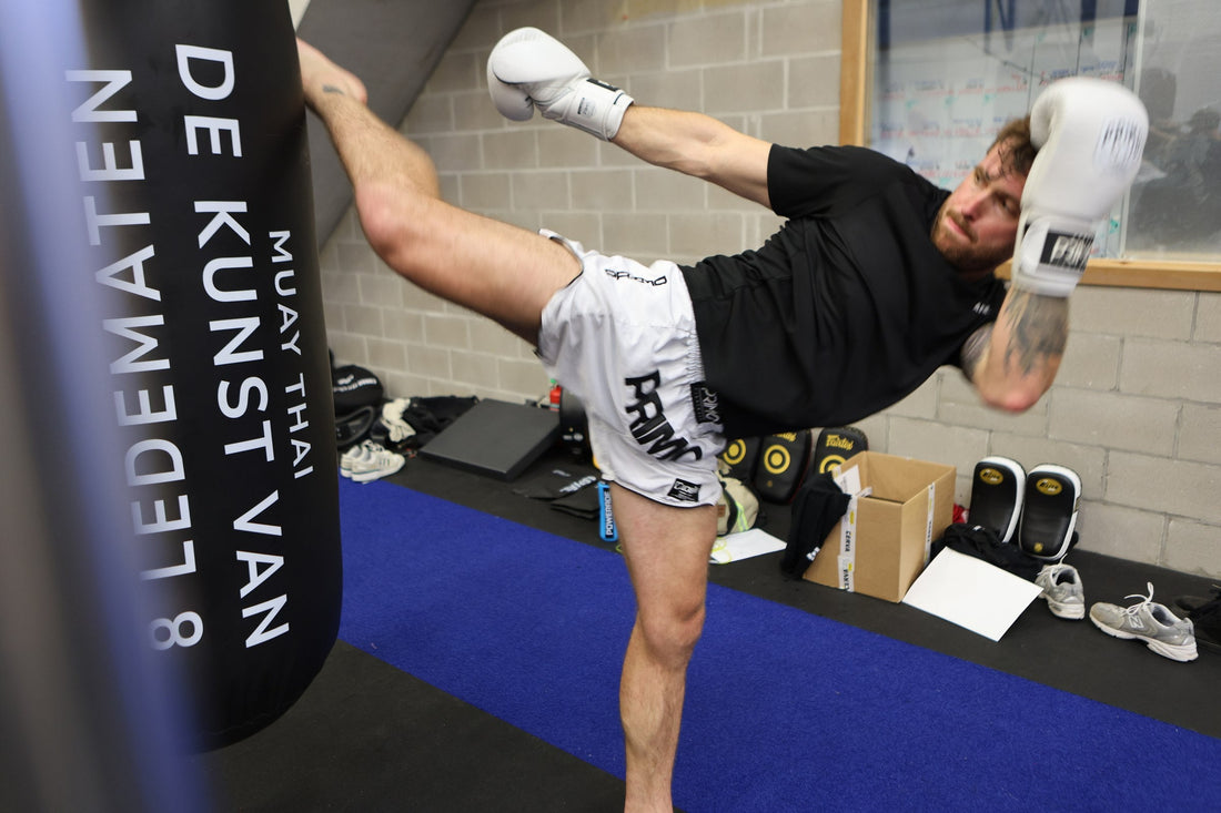 ASPIRE. athlete throwing a high kick during live sparring, ASPIRE back-print tee visible